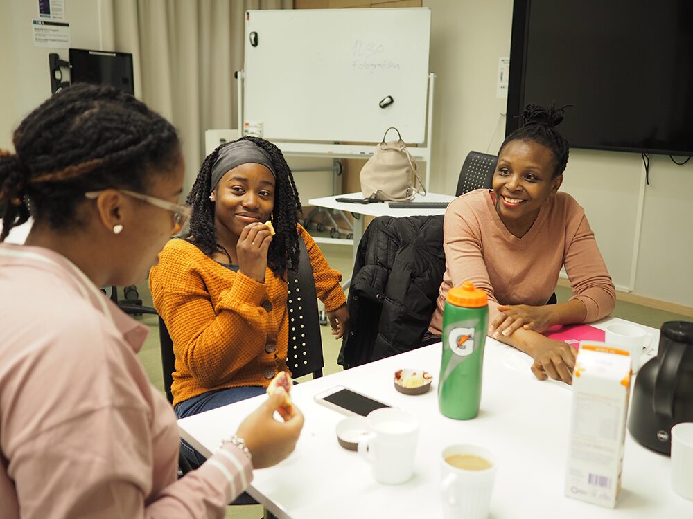 Nyamusi speaks with two DIS students over fika