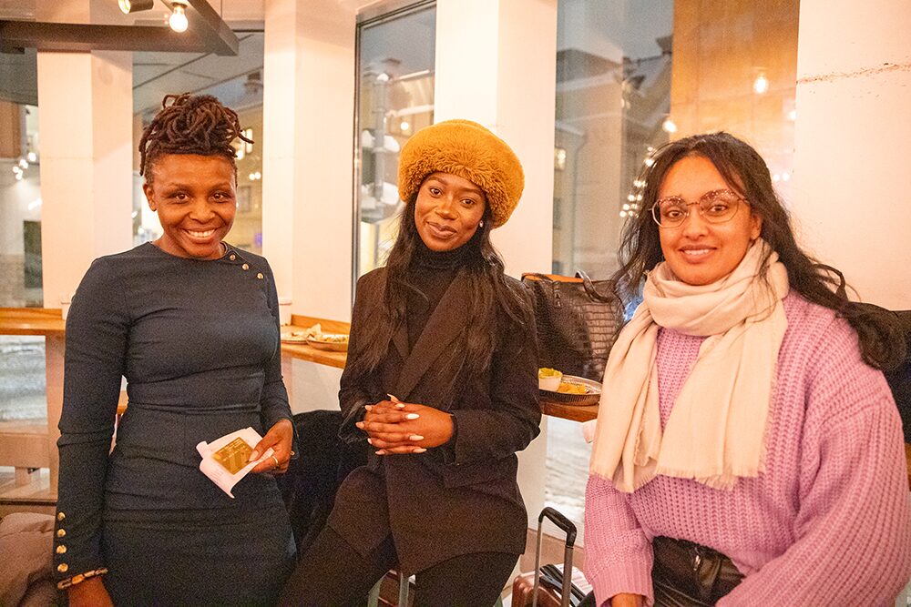 Nyamusi, Daphne, and Saba sit together and smile