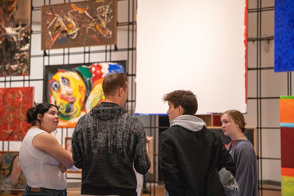 Betsy and her classmates study a wall of art
